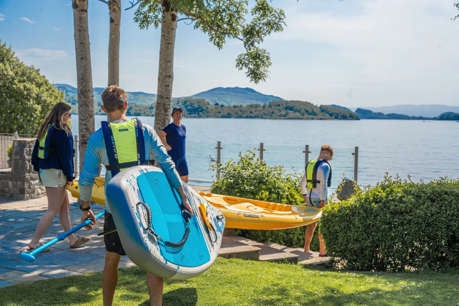 Paddlers carrying a paddleboard and kayak down to Loch Lomond