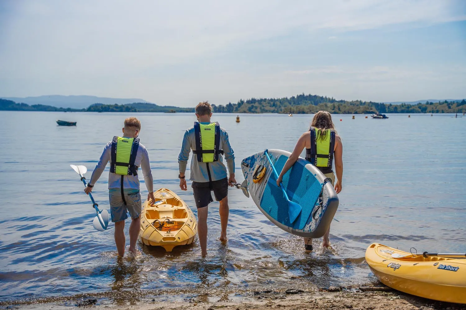 Paddlers launching kayaks and a paddleboard into Loch Lomond